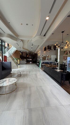 Eine großzügige Lobby mit Marmorboden, einer Treppe und einem Empfangsschalter.