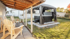 Un espace extérieur aménagé en terrasse, avec des fauteuils Adirondack en bois, un barbecue et un coin salon abrité.