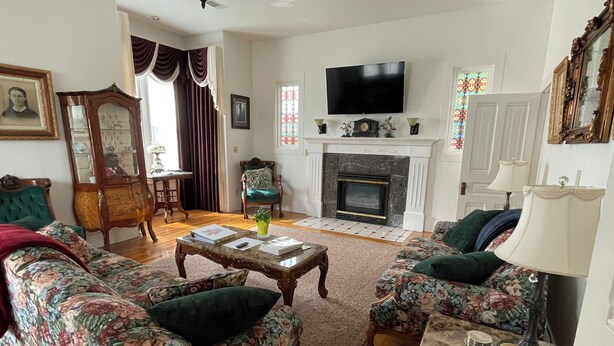 A living room with floral-patterned sofas, a wooden coffee table, a fireplace, a television, and a mirror. - Beauregard, Charming Victorian Home in Ferndale (Ferndale)