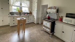 A compact kitchen with white cabinets, a stove, a microwave, and a small table with a vase. - Beauregard, Charming Victorian Home in Ferndale (Ferndale)