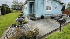 A light blue house with a front porch, a small garden with a birdbath and potted plants, and outdoor furniture. - Beauregard, Charming Victorian Home in Ferndale (Ferndale)