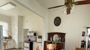 A dining area with a round table, chairs, and a ceiling fan. A kitchen is visible in the background. - Beauregard, Charming Victorian Home in Ferndale (Ferndale)
