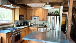 A modern kitchen with wooden cabinets, stainless steel appliances, and a large island.