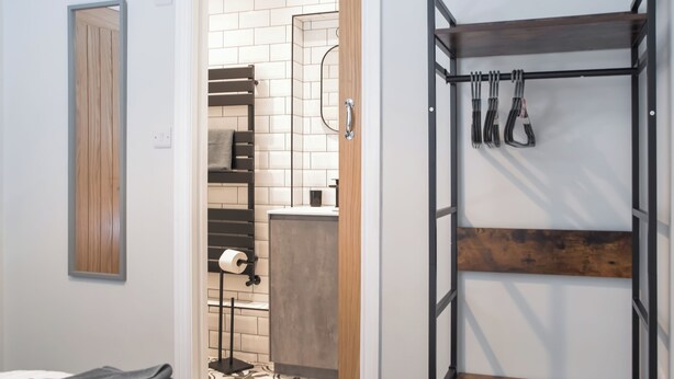 A room with a bed, a bunk bed, a bathroom with a toilet, and a towel rack.
