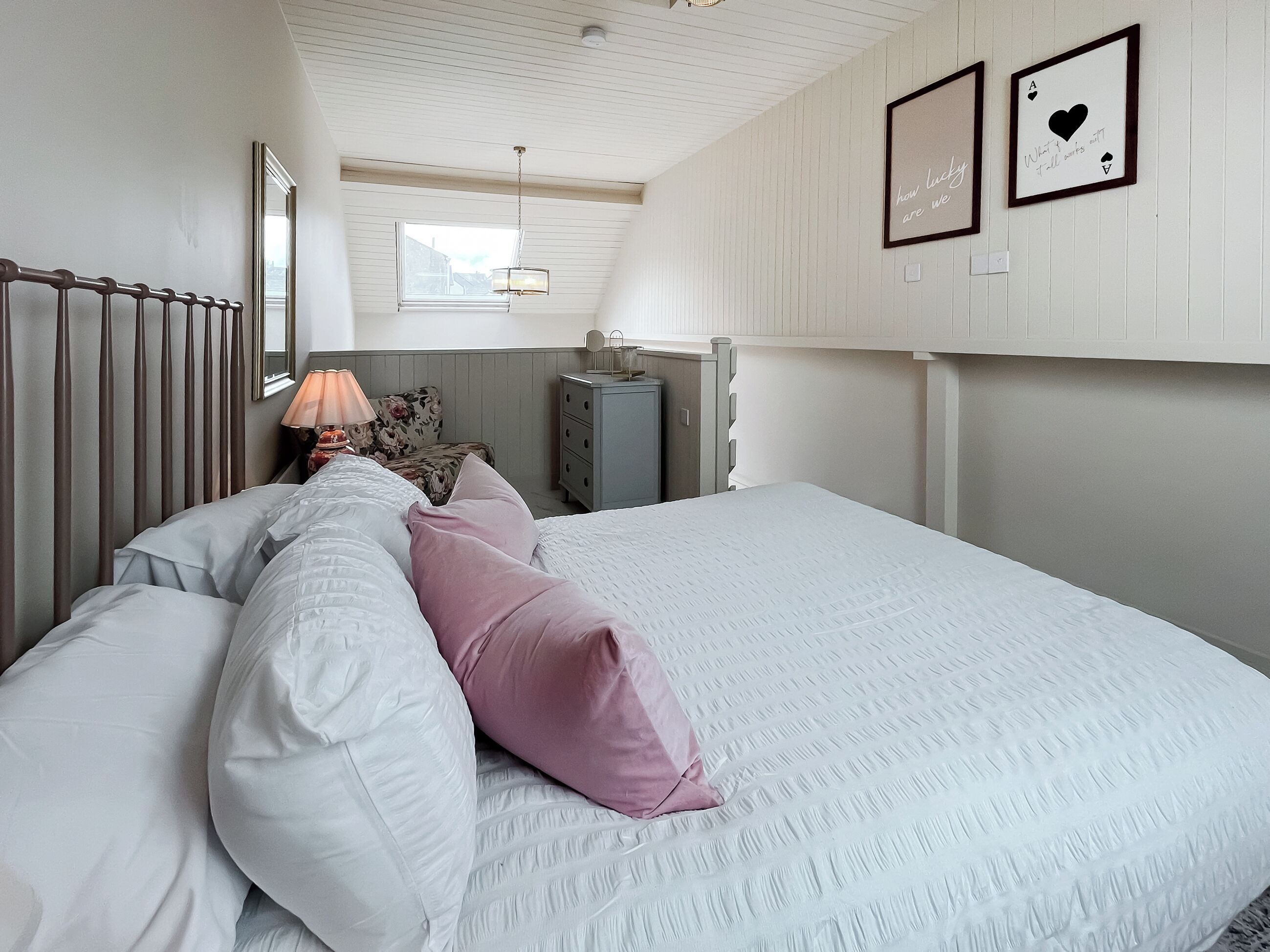 Une chambre à coucher avec un grand lit, une table de chevet, une commode et une fenêtre donnant sur un beau paysage.
