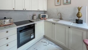 Une cuisine moderne avec des meubles blancs, un four encastré, un four à micro-ondes et un évier.
