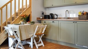 A kitchen with a wooden staircase, a dining table with chairs, and light green cabinets. - Roseland Retreat - UK49838 (Truro)