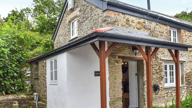 A stone house with a white exterior, a wooden porch, and a chimney. - Roseland Retreat - UK49838 (Truro)
