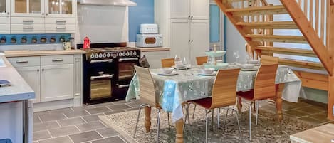 A kitchen with a stove, cabinets, and a dining area with a table and chairs.
