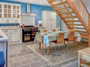 Une cuisine équipée d’un fourneau, de placards et d’un coin repas avec une table et des chaises.