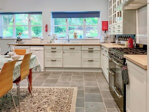 A modern kitchen with white cabinets, a gas stove, and a dining area with a table and chairs.