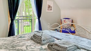 Quarto com cama, cortinas e vista para o verde lá fora.