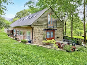 A log cabin with a stone exterior, a balcony, and a small deck area.