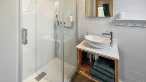 Ein modernes Badezimmer mit einer gläsernen Dusche, einem weißen Waschbecken und einer Holzwaschtisch-Möbel.