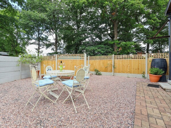 A patio with a round table and chairs, surrounded by gravel and a wooden fence. - 2 bedroom accommodation in Kyre, near Tenbury Wells (Kyre, near Tenbury Wells)