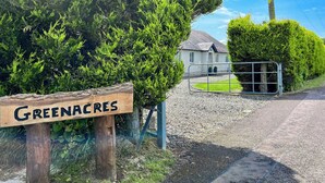 A wooden sign with 'Greenacres' written on it, a gravel driveway, a metal gate, and a house with a grey roof in the background. - 4 bedroom accommodation in Perth (Perth)