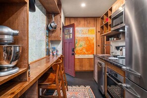 Una cucina compatta con mobili in legno, un frigorifero in acciaio inox e un forno a microonde.