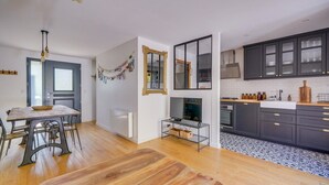 Une cuisine moderne avec des meubles de couleur sombre, un plan de travail blanc et un dosseret à motifs noir et blanc.