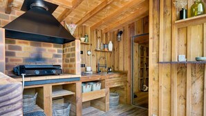 Un intérieur rustique avec des éléments en bois, notamment un four en briques, des étagères en bois et un évier.