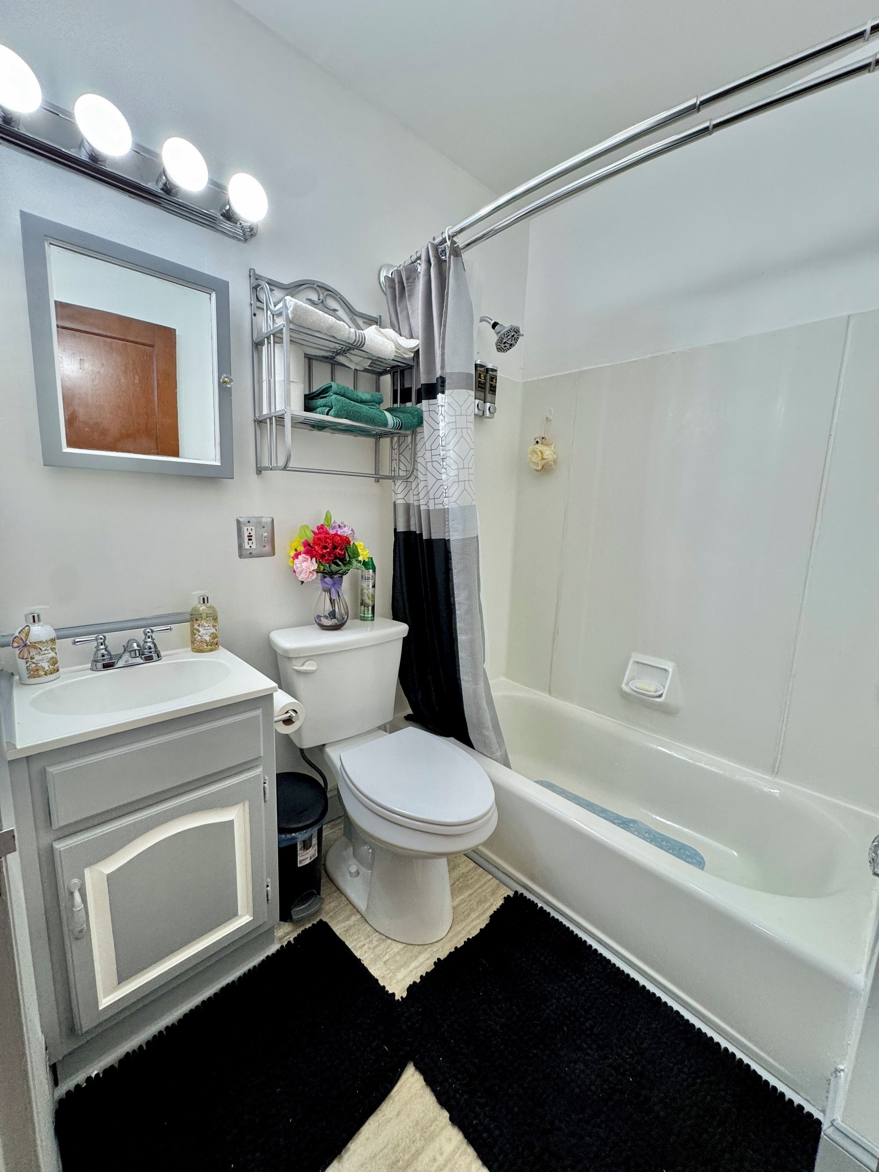 A bathroom with a toilet, sink, and bathtub. There are towels and toiletries on the wall.