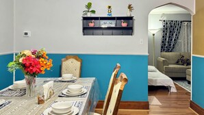 A dining area with a table set for four, a vase of flowers, and a wall-mounted shelf with decorative items. - Charming 2-bedroom apartment in Pleasant Blasdell with morning breakfast. (Blasdell)