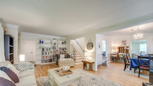 Un salon spacieux comprenant un canapé, une table basse et des étagères. Un escalier mène à une autre pièce où se trouve un coin repas.