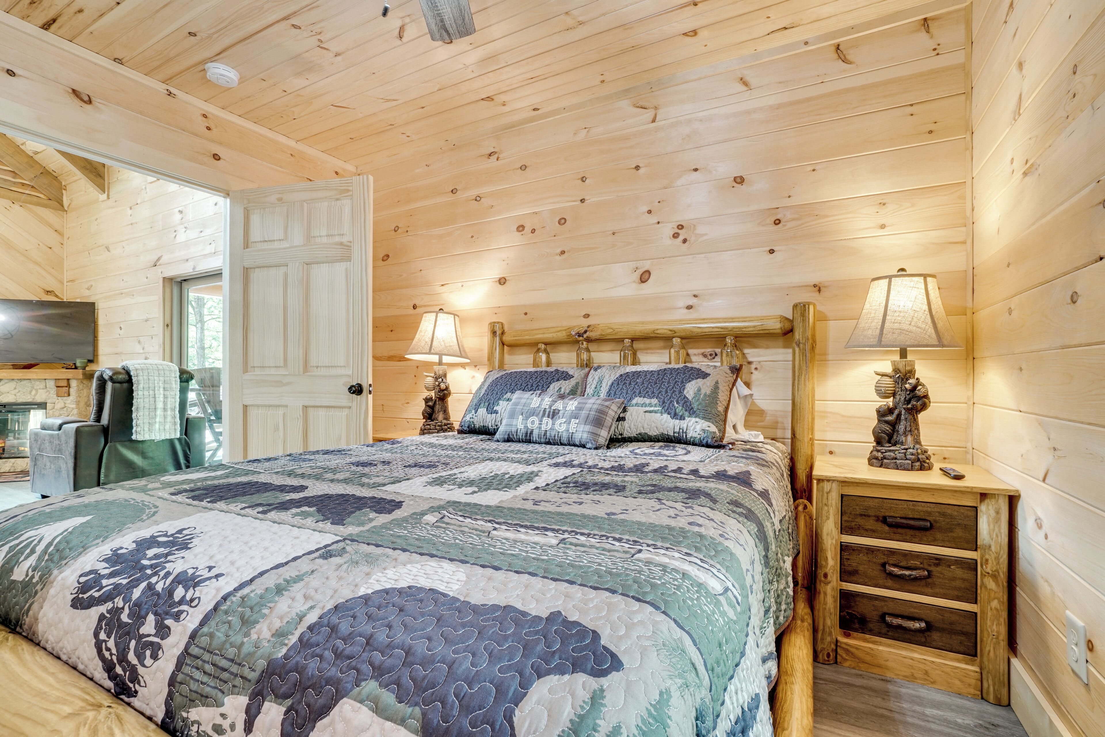 Une chambre à coucher dans un chalet en bois, avec un lit, deux lampes de chevet, une table de chevet et une commode.
