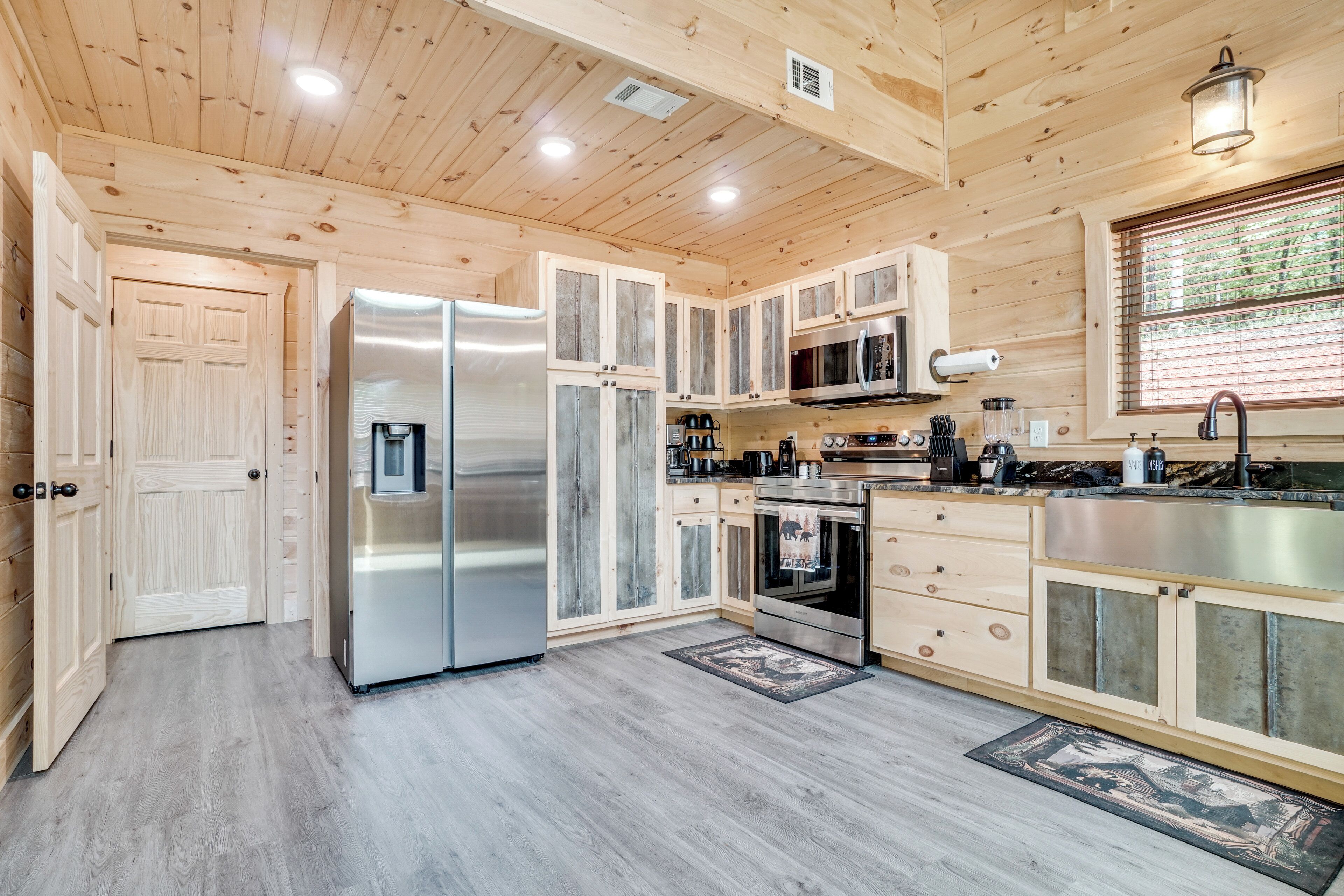A modern kitchen with wooden cabinetry, stainless steel appliances, and a large window.