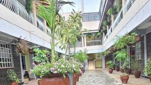 A covered walkway with hexagonal tiles, potted plants, and a central drainage grate. - Lux Suites Elmoc Apartments Nakuru (Nakuru)