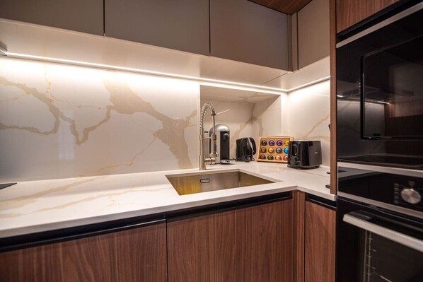 A modern kitchen with a marble backsplash, stainless steel appliances, and wooden cabinets.