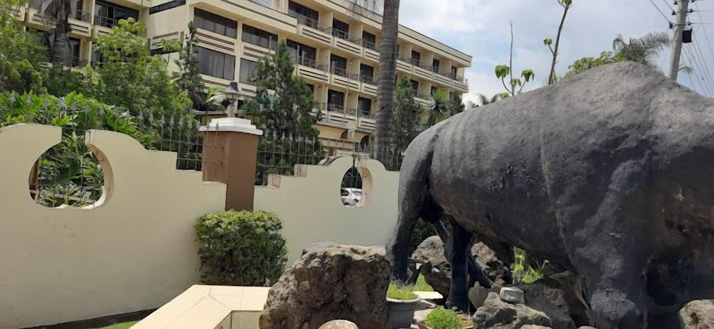 Una gran estatua negra de un animal en un espacio al aire libre, con un edificio de fondo.