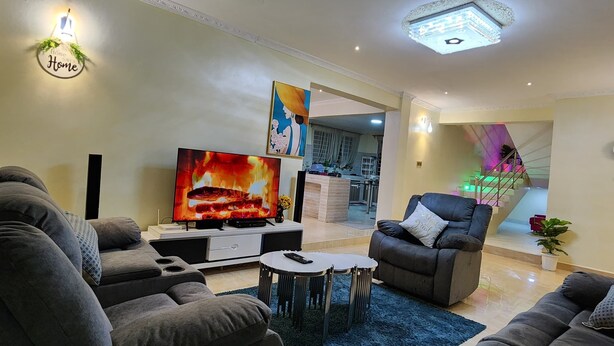 Ein modernes Wohnzimmer mit grauen Sofas, einem Flachbildfernseher und einem blauen Teppich.