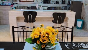 Ein Essbereich mit einem Tisch für zwei Personen, mit einer Vase voller Sonnenblumen und gestapelten Tellern.