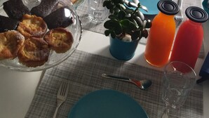 A dining table set with plates, glasses, and a dessert display. A painting of a sunset is on the wall behind the table. - B&B La Munachell  (Vieste)