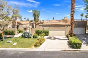 A residential house with a tiled roof, a garage, and a well-maintained lawn with various plants. - Updated Condo on Lake Mirage, Tennis, Pickleball, Pool, Spa, Gorgeous Views (Rancho Mirage)