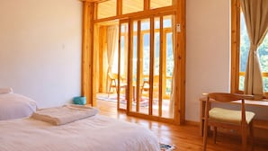 Een kamer met een bed, een stoel en een grote schuifglazen deur die uitkomt op een buitenruimte.