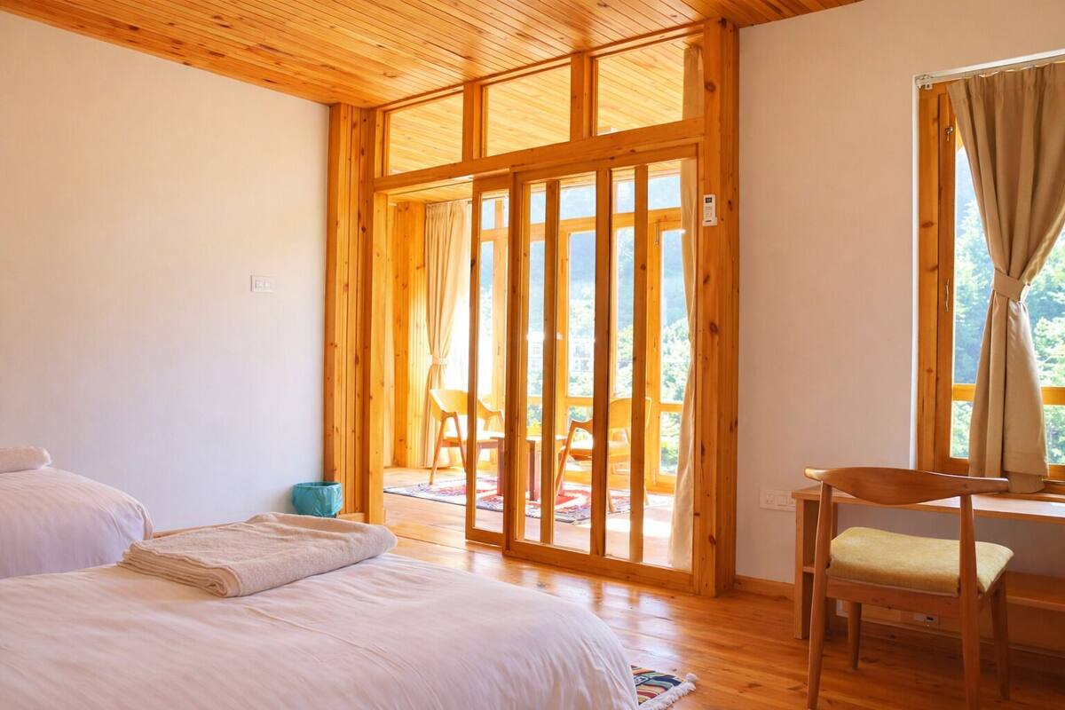 Una habitación con una cama, una silla y un amplio ventanal corredera que da a un espacio exterior.