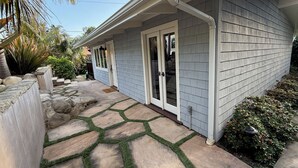 A house with a stone patio, a covered porch, and a small garden area with palm trees and shrubs. - Montectio Magic (Montecito)
