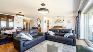 Una sala de estar moderna con un sofá modular, un comedor y una cocina al fondo.