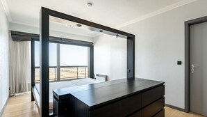 Un dormitorio moderno con un ventanal grande, un aparador de madera oscura y una puerta.