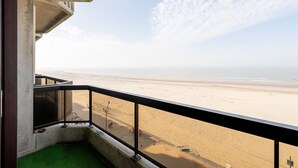 Un balcón con vista a una playa arenosa y al océano.