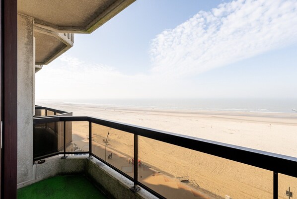 A balcony with a view of a sandy beach and ocean.