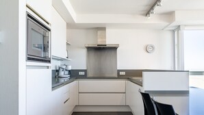 A modern kitchen with white cabinetry, a stainless steel range hood, and a built-in oven.