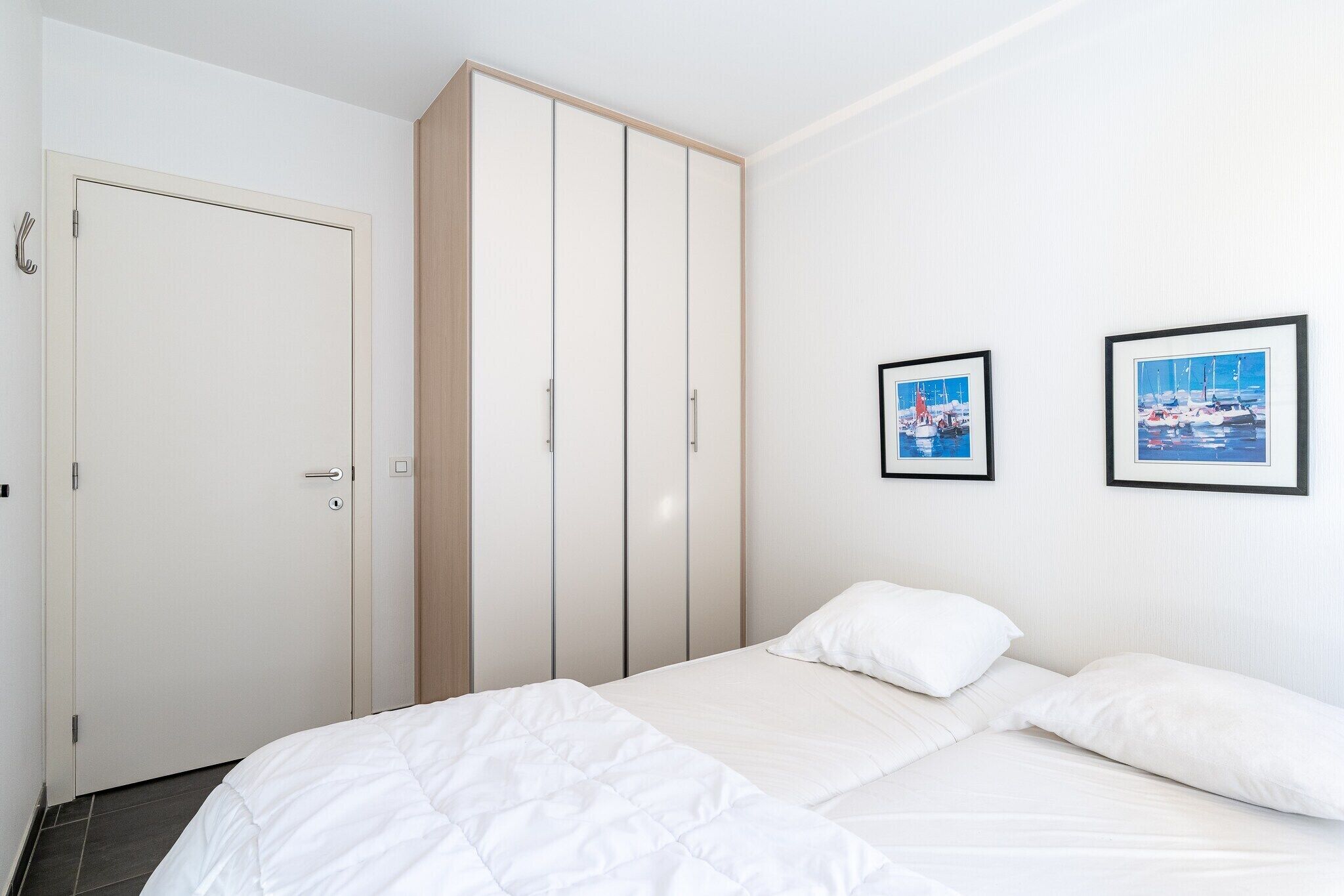 Une chambre à coucher avec un lit, une armoire et deux tableaux encadrés accrochés au mur.