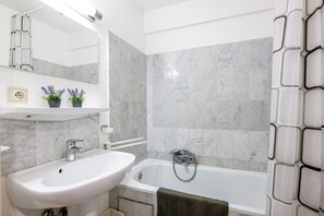 Une salle de bain avec un lavabo blanc, une baignoire et un miroir.