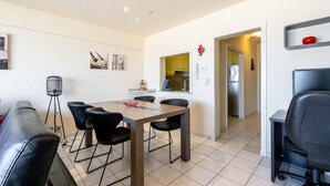 A modern living room with a dining area, a kitchen in the background, and a small office space. - Apartment in Blankenberge with Sea View (Blankenberge)