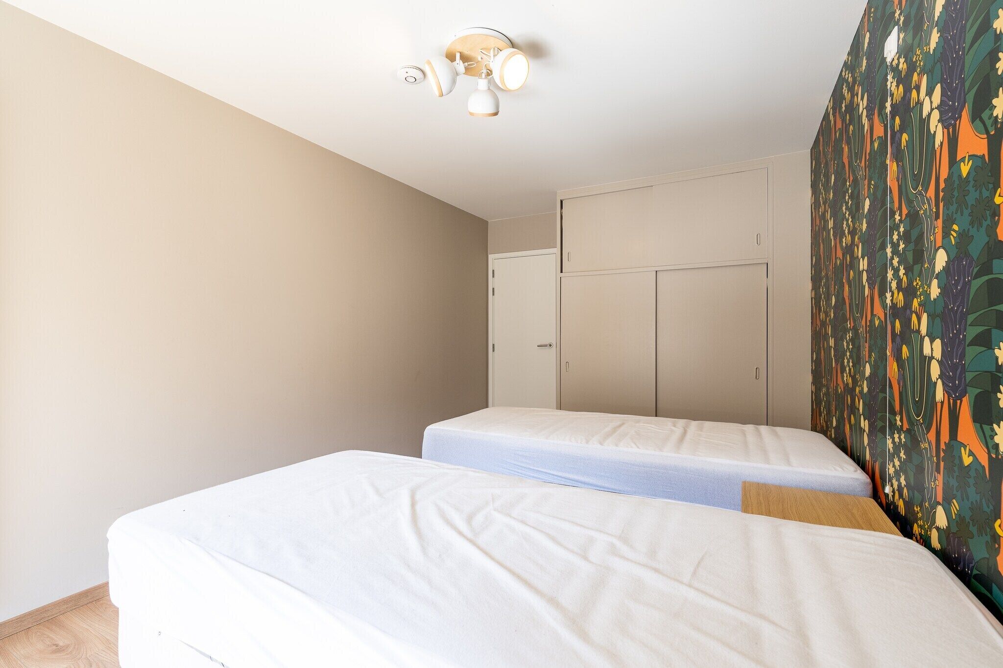 Una habitación con dos camas individuales, un ventilador de techo y un armario.