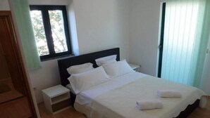 Ein Schlafzimmer mit einem Bett, Nachttischen, einem Fenster und einer Tür.