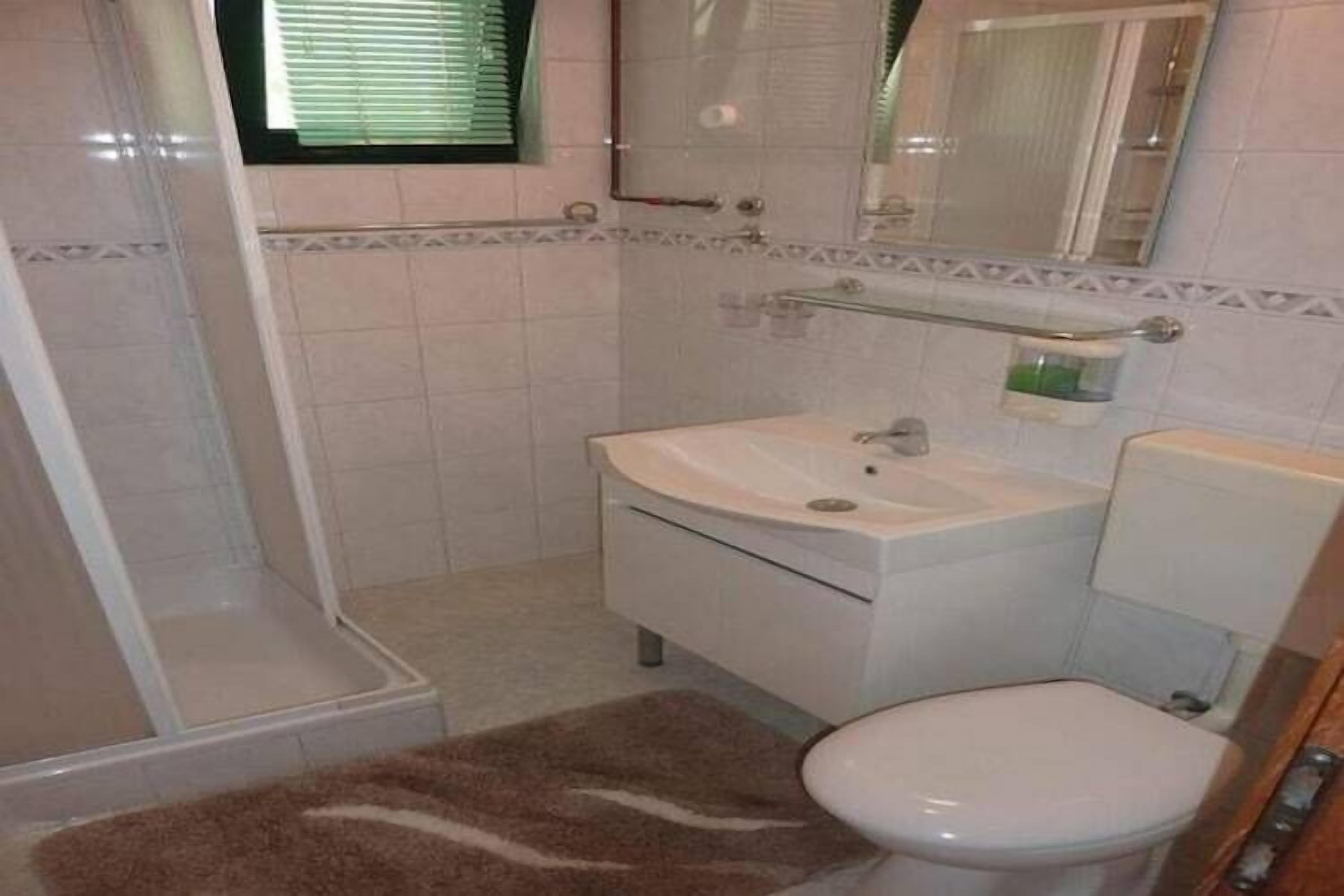 A bathroom with a toilet, sink, and shower.