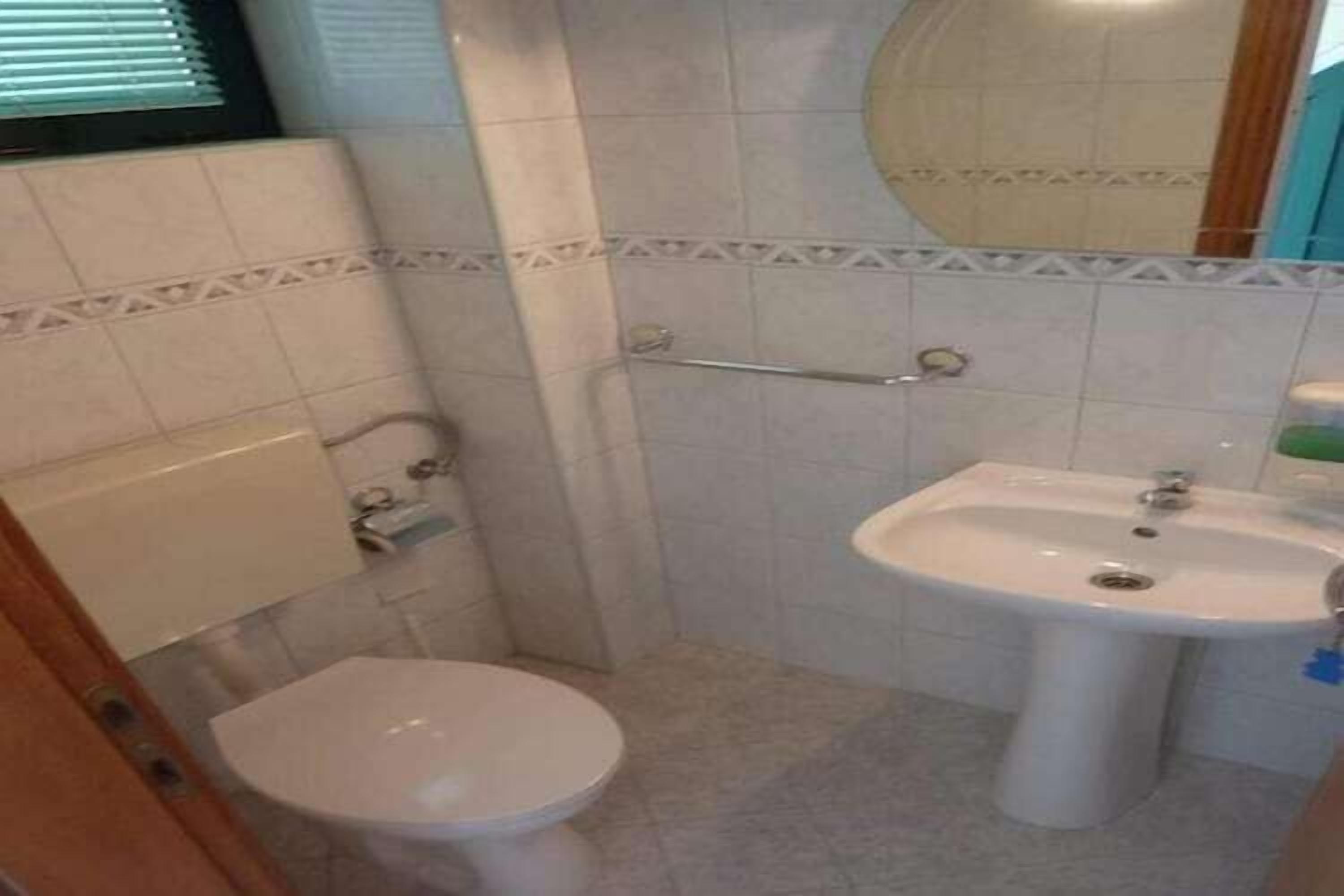 Een kleine badkamer met toilet, wastafel en spiegel.